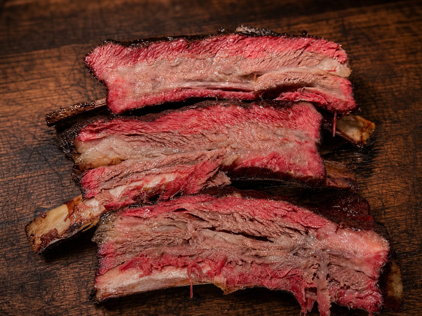 Sliced smoked beef ribs showing a deep smoke ring