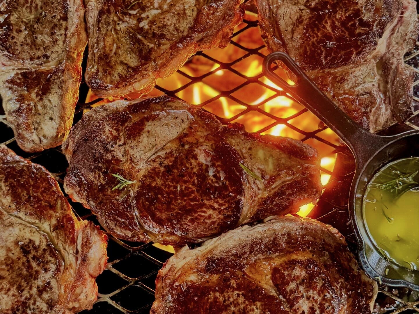 A steak grilling over glowing coals